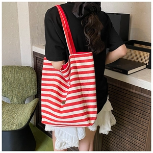 Detail of red and white striped canvas tote bag showing wide shoulder strap and side button