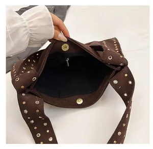 Detail of suede tote bag interior with gold studs, magnetic closure, and zip pocket