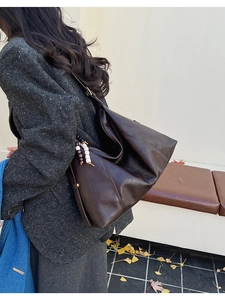 Détail d'un grand sac cabas en cuir marron foncé avec bijou de sac perlé en décor d'automne