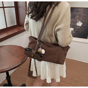 Brown suede tote bag with decorative leather glasses case shown in a cozy interior