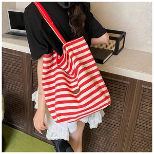Detail view of large striped tote bag featuring a vintage plaque on red and white canvas