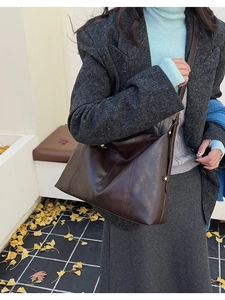 Détail d'un sac cabas en cuir marron foncé avec boucle dorée et style automnal