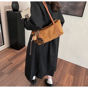 Detail of caramel suede tote bag with brown zip pouch and key charm on black coat