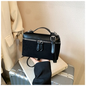 Close-up of black square bag featuring mixed leather and suede textures with silver zippers