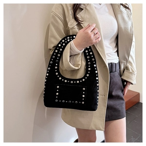 Détails des rivets argentés sur le sac en daim noir porté par un mannequin