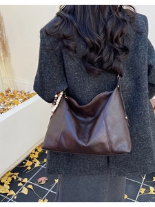Détail du sac hobo en cuir marron foncé avec perles vintage sur un manteau en tweed