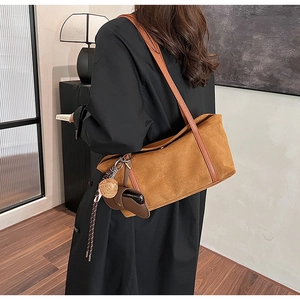 Brown suede tote bag with leather handle and branded logo on female model in stylish interior
