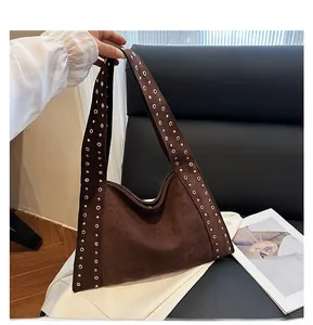 Detail of dark brown suede shoulder bag with gold metal studs on the strap edge