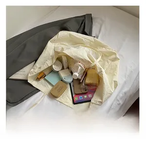 Intérieur du grand sac cabas beige montrant les objets du quotidien tels que bouteille et maquillage