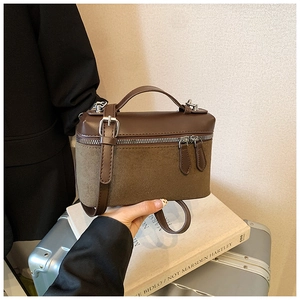 Detail of retro mini box bag with brown and olive green leather patchwork held over books