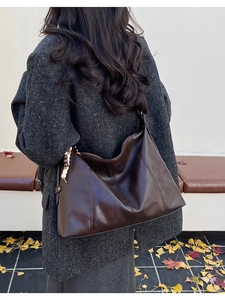 Détail du grand sac cabas marron avec pompon en perles de bois sur un manteau en tweed