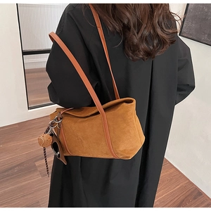 Caramel suede tote bag detail with plush bear charm on minimalist shoulder strap