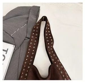 Detail of dark brown suede bag strap with decorative brass metal eyelets and rivets