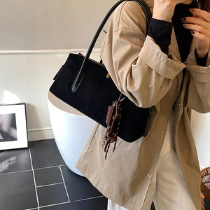 Minimalist black suede underarm bag for women with a unique chocolate pendant accessory