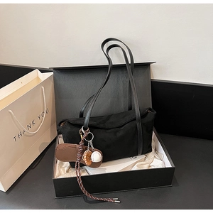 Close-up of black suede shoulder bag in premium gift box with baseball charm