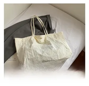 Détail de la texture plissée naturelle et de la broderie de lettres sur le sac fourre-tout
