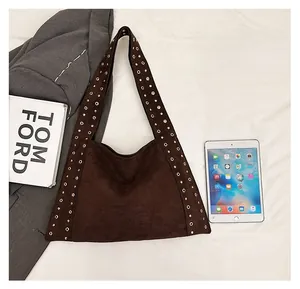 Detailed top view of large brown suede tote bag with stylish golden rivets on white fabric