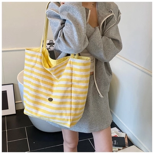 Detail of yellow and white striped canvas tote bag showing the metallic logo and texture