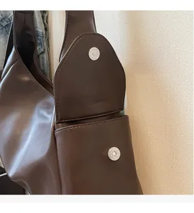 Détail du sac cabas en cuir marron foncé montrant le fermoir magnétique argenté et coutures