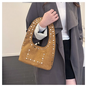 Détail du sac hobo en daim avec clous métalliques argentés et poignée découpée