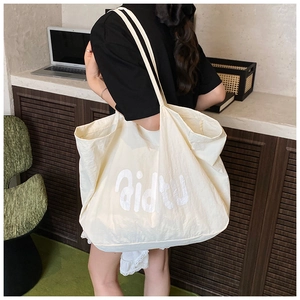 Détail d'un grand sac cabas blanc crème porté à l'épaule pour le quotidien urbain