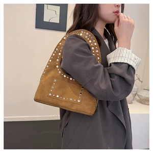 Détail de sac sous l'aisselle en daim marron orné de rivets métalliques argentés complexes