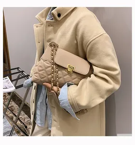 Gros plan d'un sac à bandoulière en cuir beige matelassé avec fermoir métallique