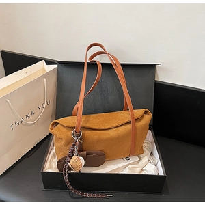 Detailed macro view of warm brown suede tote bag featuring a baseball glove charm