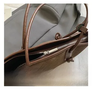 Close-up of silver metal zipper and dark brown woven texture on a large tote bag