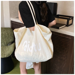 Détail d'un sac cabas blanc crème avec tissu texturé et impression artistique