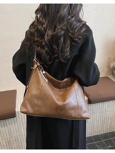 Sac fourre-tout vintage marron avec pendentif en perles porté par un mannequin en studio