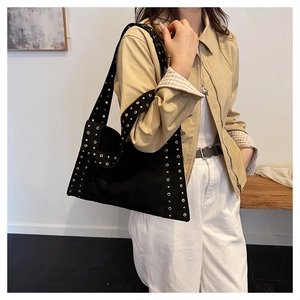 Detail view of black canvas tote bag with gold metal eyelets on the wide shoulder strap