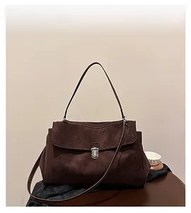 Detailed view of dark brown suede shoulder bag featuring a silver metal buckle closure