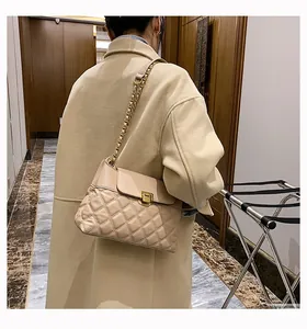 Détail du sac matelassé beige avec bandoulière chaîne dorée et fermoir métallique