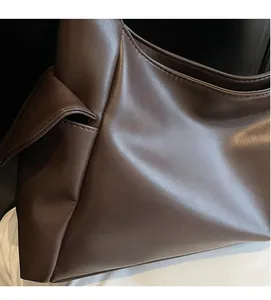 Gros plan du sac sous l'aisselle en cuir marron foncé avec détails de nœuds latéraux