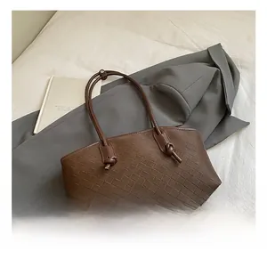 Detailed view of woven dark coffee tote bag with intricate leather texture and slim strap
