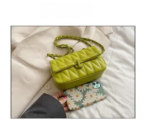 Detail view of green quilted chain bag showing compact size compared to a smartphone