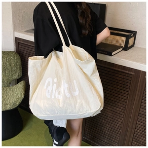 Détail d'un grand sac cabas beige en nylon avec imprimé lettre et longues bandoulières