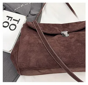 Close-up of brown suede shoulder bag featuring silver twist lock and white contrast stitching