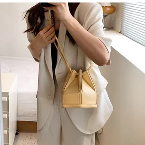 Detailed view of cream-colored geometric folding bucket bag with thin leather strap