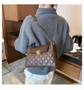 Détail du sac bandoulière marron matelassé avec fermoir doré et chaîne porté par un modèle