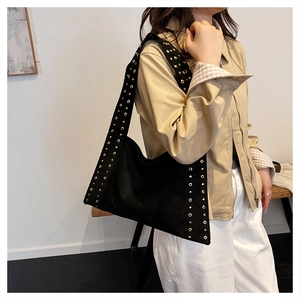 Detail of black studded underarm bag with gold rivets and wide shoulder strap