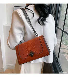 Detail shot of a brown embossed leather crossbody bag with metallic chain and clasp