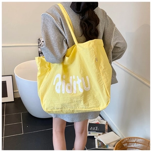 Détail du grand sac cabas jaune avec lettrage blanc et bretelles robustes pour femme