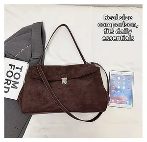 Deep brown suede shoulder bag featuring a silver metal lock next to a tablet for size