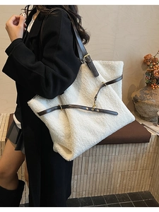 Detail of white faux shearling tote bag with dark brown leather straps and gold metal buckles