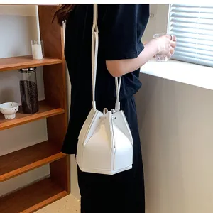 Detail of white geometric bucket bag with pleated panels and adjustable crossbody strap