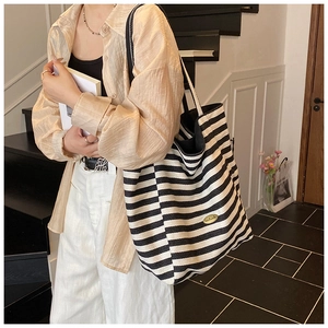 Detail of canvas tote bag with black and white stripes and leather shoulder strap