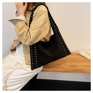Detail of black velvet motorcycle bag with gold metallic eyelet studs and side texture
