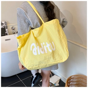 Détail du sac fourre-tout en nylon jaune vif avec inscription blanche sur le tissu